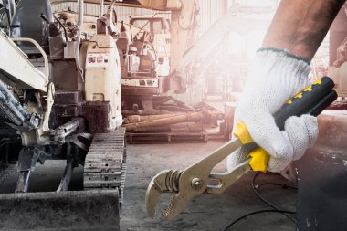 Atölyede bakım veya makine servisi için bir alet tutan bir insan eli yakın.