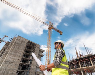 Mühendislik Danışmanlığı Elinde plan tutan şantiyede. Yapı denetçisi. Yeni binanın şantiye kontrol çizimi ve iş akışı