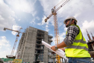 Mühendislik Danışmanlığı Elinde plan tutan şantiyede. Yapı denetçisi. Yeni binanın şantiye kontrol çizimi ve iş akışı