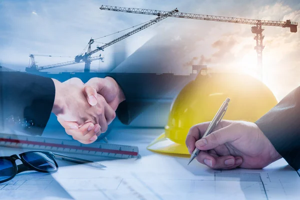 Double exposure of construction site and Business people shaking hands after the contract is signed for construction management Infrastructure plan guidelines concept.