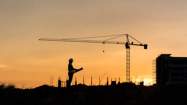 Silhouette engineer construction work control and tower crane background on natural sunset sky.,Heavy industry and building construction work concept