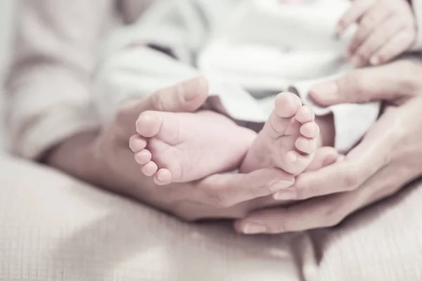 Feet of the newborn baby in parents hands. Moment of mother's care after maternity concept. Selection focuses to toe and add vintage color filter for feeling image.