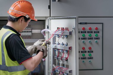 Santralin kontrol odasında kablolarla çalışan elektrikçi gençler.