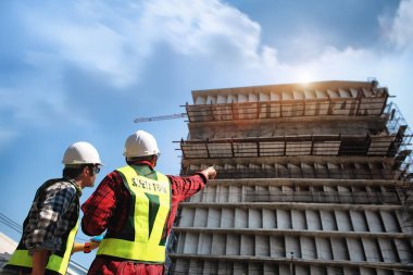 İnşaat mühendisleri, inşaat alanında veya yüksek katlı binanın şantiyelerinde danışmanla planlarla tartışıyor.