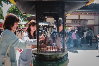 Tokyo, Japonya - Mar 2015: Turistler bu arada Tütsü brülör içine tütsü işlemeli Japon Intendant Kyoto Kinkaku-ji Tapınağı'nda tütsü brülör joss çubukları kurtulmak
