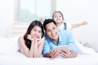 Asyalılar, evde yatak odasında mutlu bir aile. Anne, Baba ve oynayan çocuklar, Aile bireylerinin faaliyetleri üç kişinin aile sağlığı nın iyi olduğu çocukların eğitimi, Sağlık Sigortası kavramı.