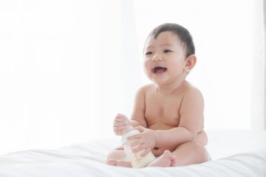 Asya Sevimli erkek bebek gülümseme yatak odasında süt gücü şişesi ile oynarken, Gıda, Süt, Asya bebek, Anne, Sağlık kavramı.