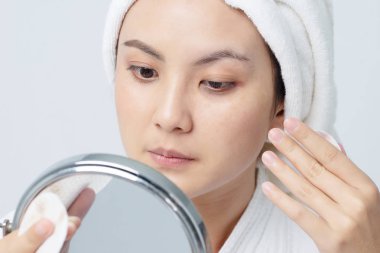 Güzel cilt bakım konsepti. Asya güzel genç kadın Pamuk Ped ile yüzünü cilt temizlik odaklanan ve ayna bakıyor.