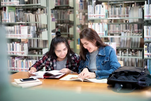 两名亚洲女学生打开阅读杂志和微笑放松在公共图书馆 在国际学院 大学学习和友谊的生活 — 图库照片
