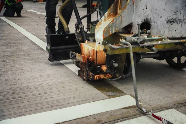 Traffic line painting jobs, Thermoplastic spray marking by machine on concrete road surface in construction. Workers are painting white traffic lines.