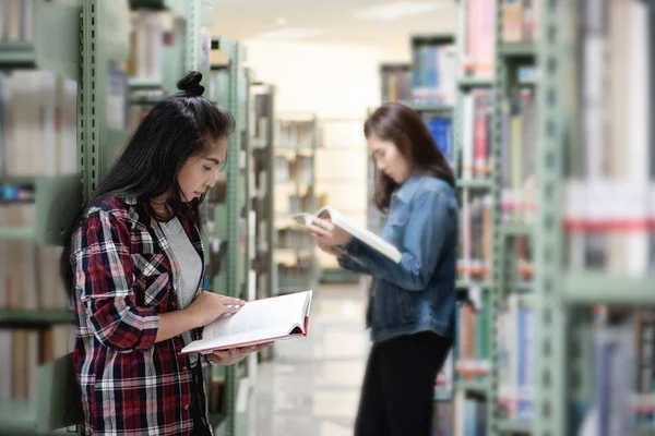 亚洲女学生在国际学院 大学图书馆的书架上打开和学习课本 — 图库照片