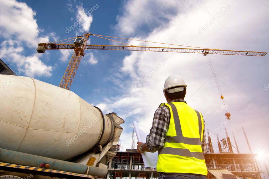 Civil Engineering people on construction site holding blueprint in his hand and looking to tower crane for concrete casting workflow of new building.