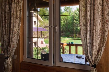 Bahçesinde penceresinden görünümü. Bahar güneşli gün. Rustik tarzı iç.