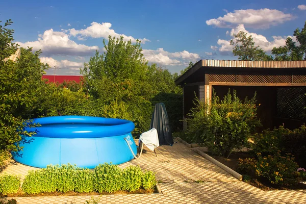 Plastik yüzme havuzunda özel bahçe. Mavi gökyüzü beyaz bulutlar ile