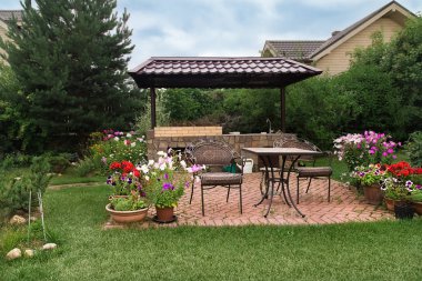 Arka bahçe veranda alan şömine ve mobilya ile. Yeşil parti alanı. Barbekü alanı. Çiçek açan çiçekler