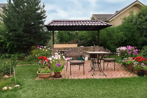 Arka bahçe veranda alan şömine ve mobilya ile. Yeşil parti alanı. Barbekü alanı. Çiçek açan çiçekler