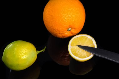 Portakal, limon, siyah arka plan üzerinde bıçak. Yarım limon. Narenciye ile natürmort.