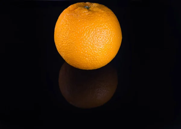 Isolated whole orange on black background.