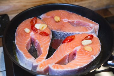 Çiğ somon fileto tava üzerinde. Somon biftek sarımsak ve kırmızı biber ile. Pişirme.