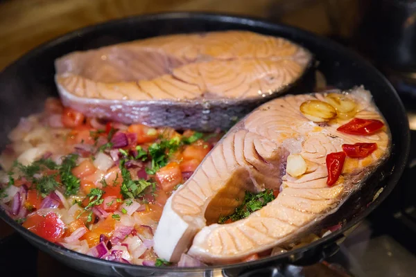 Salmon fillet on frying pan.  Two Salmon steaks with vegetables roasting on frying pan. Cooking.