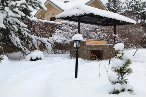 Backyard Patio.Landscape  with barbeque area, snowbanks of white snow, pine trees in country garden. Country life concept.