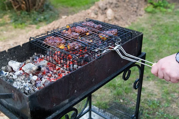 男子在户外烧烤炉上煮肉 在热煤上的金属网格上烤肉 选择性聚焦 — 图库照片