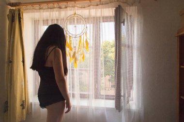 Esmer Kadın ayakta ve pencereden dışarı bakıyor - yan görünüm. 