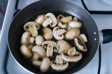 Zeytinyağında sotelenmiş küçük şampiyonlar ve doğranmış sarımsak. Kızartma tavasında mantar pişirme. Ev yapımı yemek..