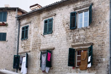 Ortaçağ tuğlalı ön camlar, kapalı ve ahşap panjurlar açılıyor ve çamaşırları kurutuluyor. Karadağ, Kotor.