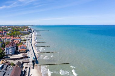 Baltık deniz kıyısının en üst manzarası. Zelenogradsk tatil köyünü, gezinti güvertesini, dalgaları, mavi denizi ve mesafeye uzanan kumlu bir sahil şeridini görebilirsiniz..