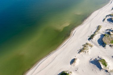 Kumsalın muhteşem kuş bakışı görüntüsü. Kum ve su arasındaki sınırı, sığlığı ve denizin derinliğini de görebilirsiniz. Bu kenarlık resmi çapraz olarak böler. İHA 'da vuruldu..