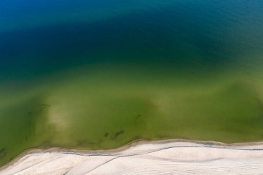 Denizin kumlu bir plajla buluştuğu bir parça. Tepeden tırnağa çekilmiş, alta dik. Su kolonundan denizin dibini görebilirsin..