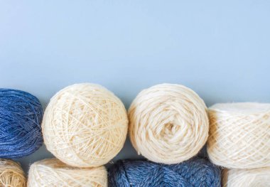Mavi arka plan üzerinde üst üste çok renkli yün iplik topları üst görünümü