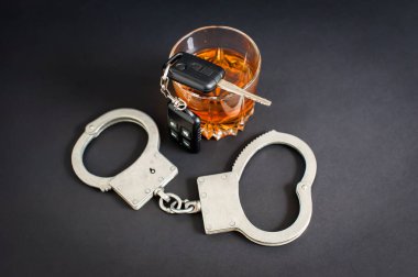Sarhoş araba kullanıyor. Alkol, araba anahtarları, siyah arka plan üzerinde kelepçe