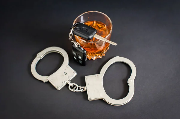 Sarhoş araba kullanıyor. Alkol, araba anahtarları, siyah arka plan üzerinde kelepçe