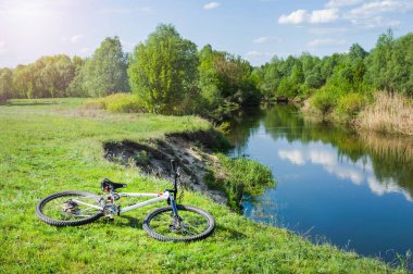 Bisiklet yaz aylarında nehir kıyısında çimenlerin üzerinde yatıyor.