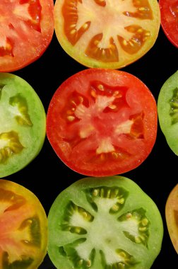 Siyah arka plan üst görünümünde kırmızı, yeşil ve sarı domates yarım
