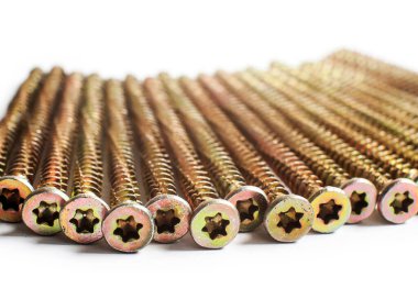 Beyaz arka planda bir sürü altın vida var. Makro