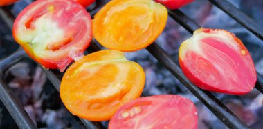 Küçük kırmızı ve sarı domates dilimleri ızgarada kızarır.