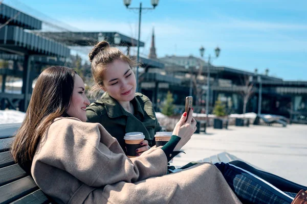 Две Студентки Сидят Скамейке Городском Парке Смотрят Смартфон Генерация Гаджетов — стоковое фото