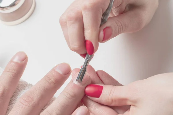 Men\'s manicure. hands of the beautician treated cuticle of male hands using pusher, scraper.