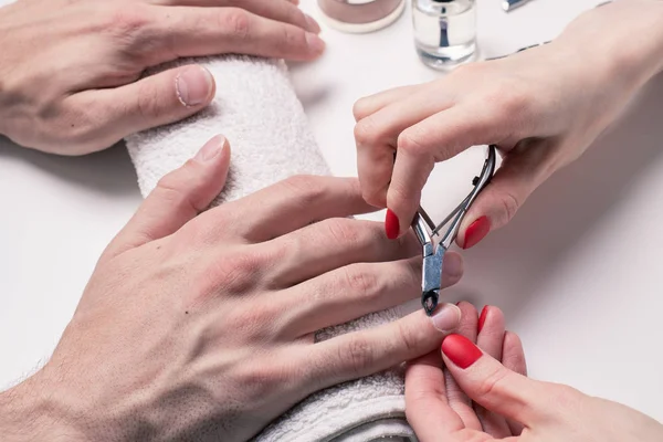 Men's manicure. woman beautician treats cuticles of dry male hands.