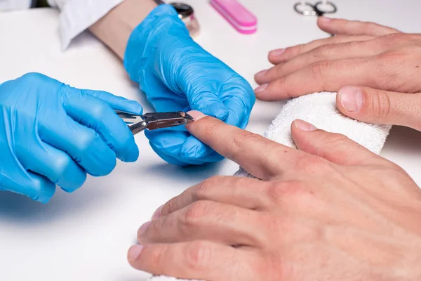 Mannen manicure. Schoonheidsspecialist in rubberen handschoenen snijdt nagelriemen op mannen handen — Stockfoto