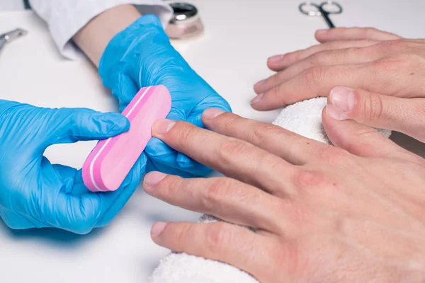 Mannen manicure. Schoonheidsspecialist in rubber handschoenen bestand nagels op mannelijke handen. — Stockfoto