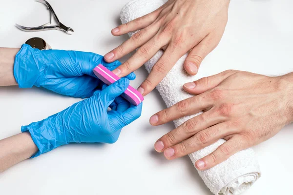 Mannen manicure. Schoonheidsspecialist in rubber handschoenen bestand nagels op mannelijke handen. — Stockfoto