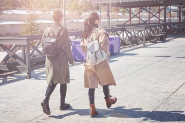 İki genç arkadaşlar şık kat ve sırt çantası Kazan şehir meydanında yürüyüş