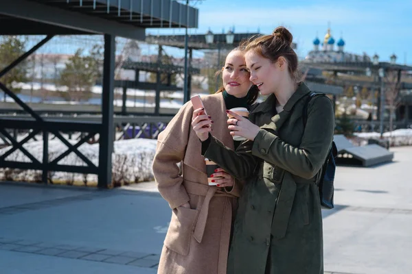 Два юных студента-путешественника в пальто на прогулке по улицам Казани, пользуются смартфоном с навигатором — стоковое фото