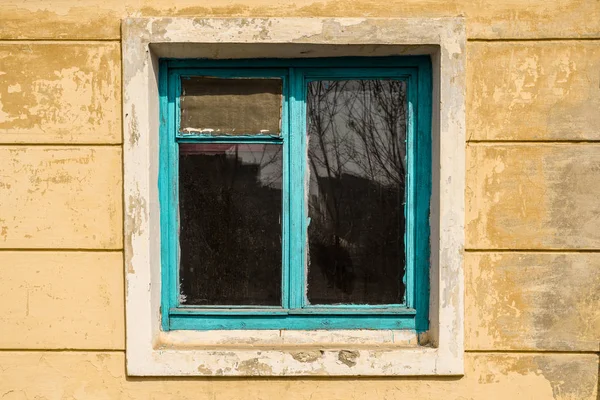 Mavi ahşap çerçeve ile terk edilmiş bir evde eski pencere.
