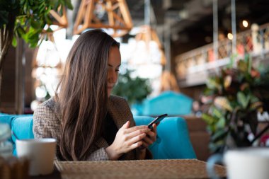 Genç esmer ile smartphone ile arka plan bulanık restoranda elinde.