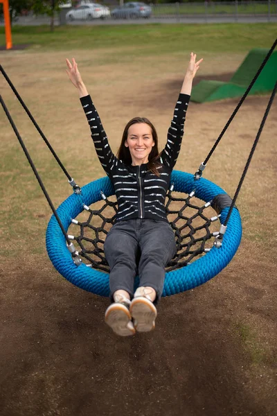 Top view of young woman swinging on hanging swing hands up smiling, concept of freedom, day off, remember childhood.